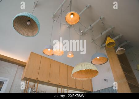 Le luci a sospensione, ciascuna con una texture unica, sono appese graziosamente sopra gli eleganti mobili in legno, emettendo una calda luce soffusa che accentua l'eleganza contemporanea Foto Stock