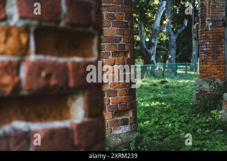 Vecchie colonne di mattoni rossi in rovina. L'ingresso della vecchia stalla rovinata Foto Stock