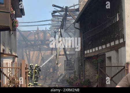 Walzbachtal, Germania. 11 agosto 2024. I vigili del fuoco estinguono l'incendio in un fienile in una zona residenziale densamente edificata nel distretto di Karlsruhe. Una persona è stata ferita e portata in ospedale. La polizia inizialmente ipotizzò che l'incendio fosse causato da un difetto tecnico. Crediti: Igor Myroshnichenko/onw-images/dpa/Alamy Live News Foto Stock