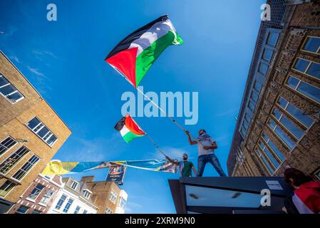 Due manifestanti maschili inondano bandiere nazionali sul tetto della fermata dell’autobus, durante la dimostrazione “MAI PIÙ È ORA”. Una piccola manifestazione a Utrecht è quella di riportare ancora una volta alla ribalta la situazione del popolo palestinese a Gaza e il continuo genocidio perpetrato su di esso dall'IDF (forza di difesa israeliana). Mentre i leader occidentali cantano ancora la stessa questione del diritto di auto-sfida di Israele in una terra occupata. Il Ministero della salute a Gaza dal 9 agosto, afferma che almeno 39.699 persone sono morte, tra cui più di: 15.000 bambini uccisi. Feriti: Più di 91.722 e 10.000 missin Foto Stock