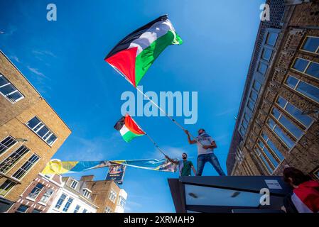 Due manifestanti maschili inondano bandiere nazionali sul tetto della fermata dell’autobus, durante la dimostrazione “MAI PIÙ È ORA”. Una piccola manifestazione a Utrecht è quella di riportare ancora una volta alla ribalta la situazione del popolo palestinese a Gaza e il continuo genocidio perpetrato su di esso dall'IDF (forza di difesa israeliana). Mentre i leader occidentali cantano ancora la stessa questione del diritto di auto-sfida di Israele in una terra occupata. Il Ministero della salute a Gaza dal 9 agosto, afferma che almeno 39.699 persone sono morte, tra cui più di: 15.000 bambini uccisi. Feriti: Più di 91.722 e 10.000 missin Foto Stock