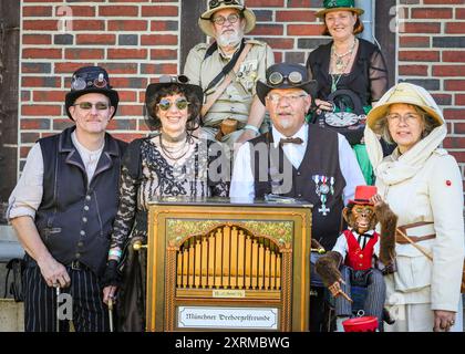 Henrichenburg, Waltrop, Germania. 11 agosto 2024. Wolfgang posa con il suo organo meccanico ('Drehorgel') e i suoi amici steampunk. I fan dello steampunk, i gruppi e i visitatori, molti in costumi d'epoca retrò-futuristica o vittoriana, si divertiranno l'ultimo giorno dell'annuale Festival del Giubileo di Steampunk. Quest'anno, il festival coincide con il 125° anniversario dello storico ascensore Henrichenburg Boat Lift, sito patrimonio industriale patrimonio storico lungo il canale Dortmund-EMS. Crediti: Imageplotter/Alamy Live News Foto Stock