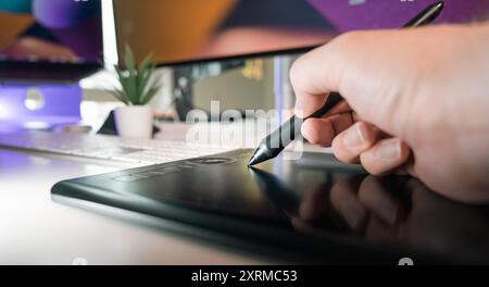 Apparecchiature per studi di grafica. Mano che tiene la penna digitale. Interni di casa e ufficio. Foto Stock