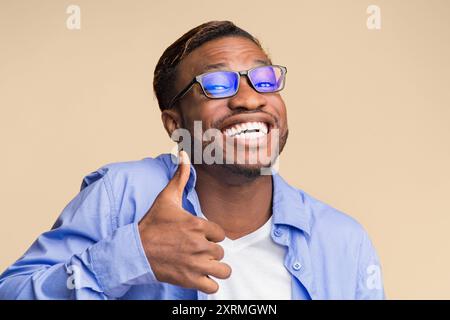 Funny uomo nero gesticolando pollice in alto standing, Studio Shot Foto Stock