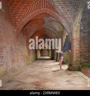 Donna sportiva che indossa un supporto a mano contro un muro arcuato. Foto Stock