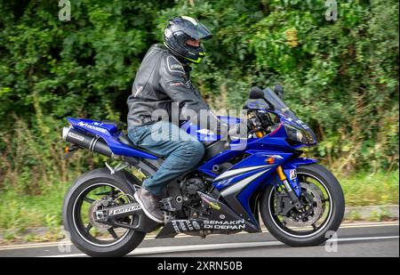 Potterspury, Northants, Regno Unito - 11 agosto 2024: Uomo a bordo di una moto Yamaha YZF R1 del 2007 blu che viaggia su una strada britannica Foto Stock