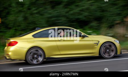 Potterspury, Northants, Regno Unito - 11 agosto 2024: 2014 BMW M4 gialla che viaggiano su una strada britannica Foto Stock