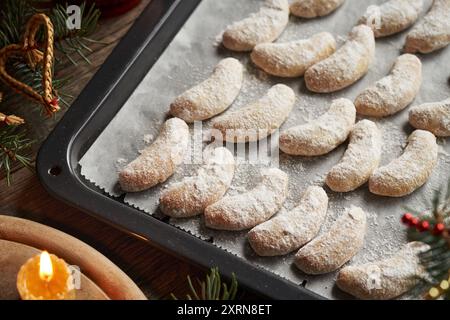 Dolce su una teglia da forno - crescenti di vaniglia fatte in casa o Kipferl, biscotti tradizionali di Natale con decorazioni natalizie Foto Stock