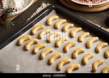 Preparazione di mezzaluna di vaniglia fatte in casa o Kipferl, biscotti di Natale tradizionali - pasta cruda su una teglia da forno Foto Stock