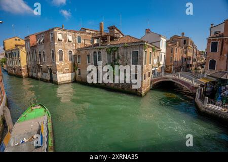 Venezia, Italia - 5 giugno 2024: Raccolta rifiuti a Venezia. Edifici sul Canal grande, con battello per la raccolta dei rifiuti. The Migrant Child art di Banksy on Th Foto Stock