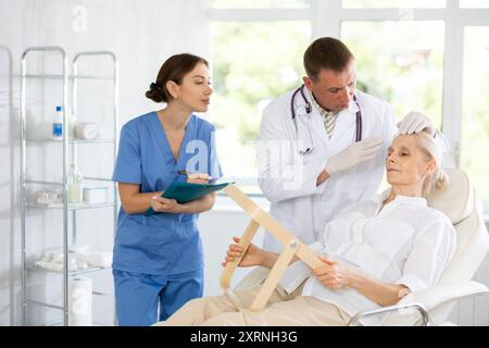 Estetista maschile che dà consulenza a paziente donna con specchio in clinica estetica Foto Stock