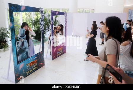 SHANGHAI, CINA - 10 AGOSTO 2024 - i fan dell'animazione e i blogger di celebrità di Internet si mettono in posa per un selfie Cosplay con foto di poster durante la premiere Foto Stock