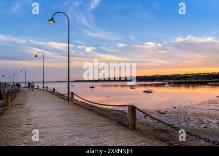 Cancale, Francia - 19 luglio 2024: Tranquillo tramonto sul lungomare con lampade d'epoca, barche e camminatori. Foto Stock