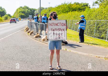 Selby, Regno Unito. 11 AGOSTO 2024. Lady porta il cartello "ingiunzione ingiustizia" poiché circa 50 manifestanti riuniti per manifestare contro la centrale elettrica di Drax, affermano che le stazioni che utilizzano "pellet di legno" come sostituto del carbone stanno causando la deforestazione di massa, ciò accade quando a Drax è stata concessa un'ingiunzione contro i manifestanti del clima e 22 membri del gruppo Recorder The Power sono stati arrestati preventivamente prima di un pianificato squat di più giorni a Drax. Credito Milo Chandler/Alamy Live News Foto Stock