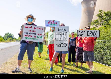 Selby, Regno Unito. 11 AGOSTO 2024. I dimostranti hanno una varietà di segnali, in quanto circa 50 manifestanti riuniti per manifestare contro la centrale elettrica Drax, affermano che le stazioni che utilizzano "pellet di legno" come sostituto del carbone causano la deforestazione di massa, ciò accade quando a Drax è stata concessa un'ingiunzione contro i manifestanti del clima e 22 membri del gruppo Recorder The Power sono stati arrestati preventivamente prima di un pianificato squat di più giorni a Drax. Credito Milo Chandler/Alamy Live News Foto Stock