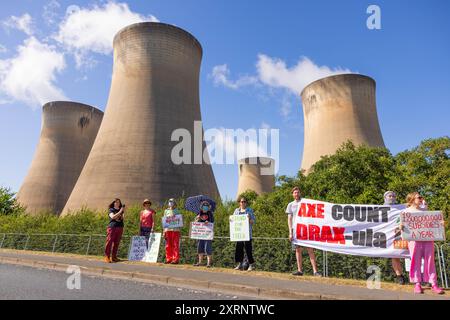 Selby, Regno Unito. 11 AGOSTO 2024. I dimostranti hanno una varietà di segnali, in quanto circa 50 manifestanti riuniti per manifestare contro la centrale elettrica Drax, affermano che le stazioni che utilizzano "pellet di legno" come sostituto del carbone causano la deforestazione di massa, ciò accade quando a Drax è stata concessa un'ingiunzione contro i manifestanti del clima e 22 membri del gruppo Recorder The Power sono stati arrestati preventivamente prima di un pianificato squat di più giorni a Drax. Credito Milo Chandler/Alamy Live News Foto Stock