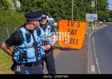 Selby, Regno Unito. 11 AGOSTO 2024. Il dimostratore ha il cartello "Eat Trees" (Eat Trees) dato che circa 50 manifestanti riuniti per manifestare contro la centrale elettrica Drax, affermano che le stazioni che utilizzano "pellet di legno" in sostituzione del carbone stanno causando la deforestazione di massa, ciò accade quando a Drax è stata concessa un'ingiunzione contro i manifestanti del clima e 22 membri del gruppo Recorder The Power sono stati arrestati preventivamente prima di un pianificato squat di più giorni a Drax. Credito Milo Chandler/Alamy Live News Foto Stock