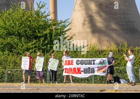 Selby, Regno Unito. 11 AGOSTO 2024. I dimostranti hanno una varietà di segnali, in quanto circa 50 manifestanti riuniti per manifestare contro la centrale elettrica Drax, affermano che le stazioni che utilizzano "pellet di legno" come sostituto del carbone causano la deforestazione di massa, ciò accade quando a Drax è stata concessa un'ingiunzione contro i manifestanti del clima e 22 membri del gruppo Recorder The Power sono stati arrestati preventivamente prima di un pianificato squat di più giorni a Drax. Credito Milo Chandler/Alamy Live News Foto Stock