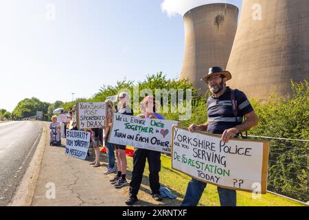 Selby, Regno Unito. 11 AGOSTO 2024. I dimostranti hanno una varietà di segnali, in quanto circa 50 manifestanti riuniti per manifestare contro la centrale elettrica Drax, affermano che le stazioni che utilizzano "pellet di legno" come sostituto del carbone causano la deforestazione di massa, ciò accade quando a Drax è stata concessa un'ingiunzione contro i manifestanti del clima e 22 membri del gruppo Recorder The Power sono stati arrestati preventivamente prima di un pianificato squat di più giorni a Drax. Credito Milo Chandler/Alamy Live News Foto Stock