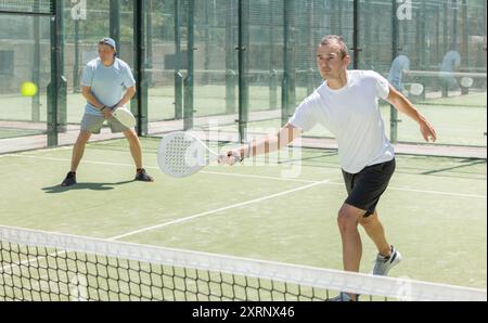 Padel gioco - l'uomo con i partner gioca in campo Foto Stock