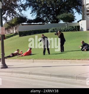 Testimoni deposti in erba subito dopo l'assassinio del presidente degli Stati Uniti John Kennedy. Bill e Gayle Newman coprono i loro figli, Clayton e Billy (nascosto) a sinistra, fotografi, tra cui White House Motion Picture Photographer, tenente Thomas M. Atkins (a destra), film al centro, Dealey Plaza, Dallas, Texas, USA, Cecil Stoughton, White House Photographs, 22 novembre 1963 Foto Stock