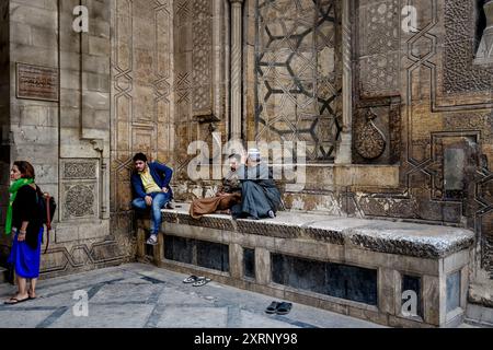 Guardiani seduti fuori dal portale d'ingresso alla Moschea del Sultano Hasan al Cairo Foto Stock