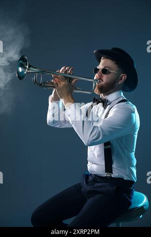 Musicista professionista che suona tromba su sfondo scuro Foto Stock