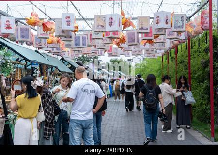 Suzhou, Cina - 11 giugno 2024: Una vivace strada di mercato a Suzhou, in Cina, con lanterne colorate e bancarelle che vendono vari prodotti. Le persone esplorano Foto Stock