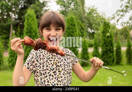 Una bambina con piacere mangia shish kebab. Foto Stock