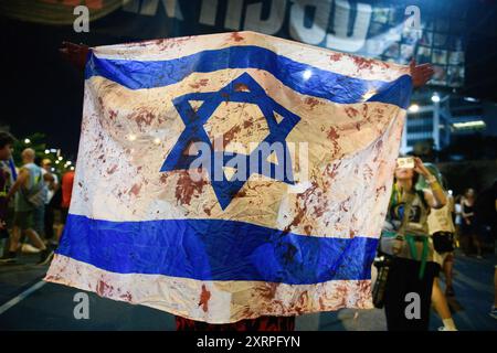 Tel Aviv, Israele. 10 agosto 2024. Un manifestante detiene una bandiera israeliana con sangue finto durante la manifestazione. Migliaia di israeliani hanno manifestato con le famiglie degli ostaggi contro il primo ministro Benjamin Netanyahu, chiedendo un accordo immediato con gli ostaggi e il cessate il fuoco, mentre Israele attende l'attacco iraniano e di Hezbollah. Credito: SOPA Images Limited/Alamy Live News Foto Stock