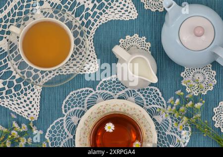 Festa del tè vintage alle cinque. Tè pomeridiano con latte. Tavolo con vista dall'alto di colore blu scuro decorato con tovaglioli retrò e fiori selvatici. Foto Stock