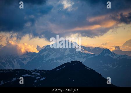 Tramonto emozionante, ombre e luce solare calda sulla cima Piazzi e sulle montagne. Cielo spettacolare con nuvole impressionanti. Alpi. Europa. Foto Stock