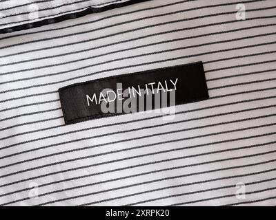 Etichetta di abbigliamento nera che mostra il Made in Italy su una camicia a righe, concept per il savoir faire e l'industria della moda italiana Foto Stock