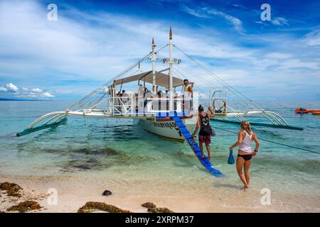 Barche tradizionali ormeggiate al largo di una piccola spiaggia tropicale dell'isola di Kalanggaman, Malapascua, Cebu, Filippine Foto Stock