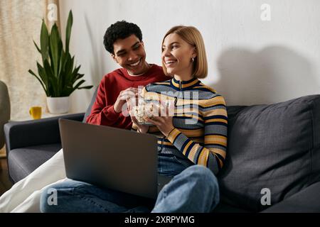 Una coppia multiculturale gode di una rilassante serata di film nel loro moderno appartamento. Foto Stock