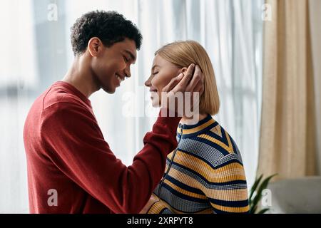 Una coppia felice e multiculturale gode di un momento tenero insieme nel loro moderno appartamento. Foto Stock