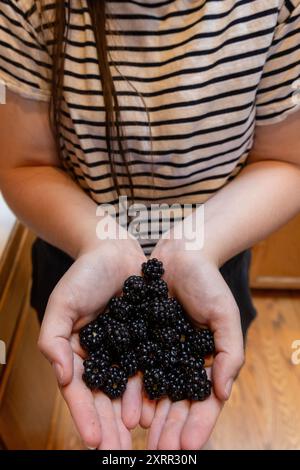 Donna che tiene una manciata di more fresche a forma di cuore Foto Stock