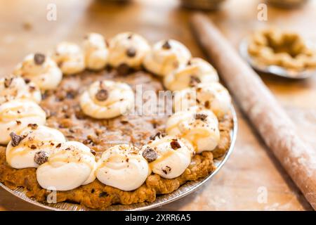 Una torta appena sfornata con panna montata, gocce di cioccolato, Foto Stock