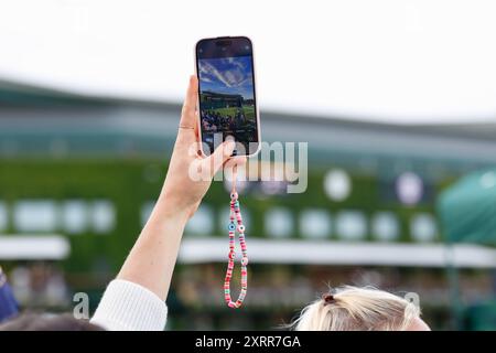 Donna che regge il cellulare per scattare una foto ai campionati di Wimbledon del 2024, Londra, Inghilterra. Foto Stock