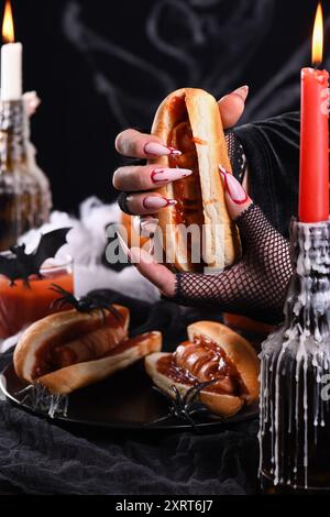 Hot dog Bloody Fingers nelle mani di una strega. Antipasto di Halloween Foto Stock