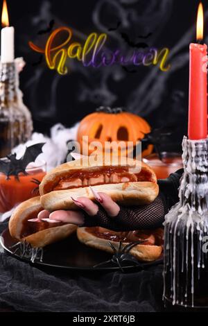 Hot dog Bloody Fingers nelle mani di una strega. Antipasto di Halloween Foto Stock