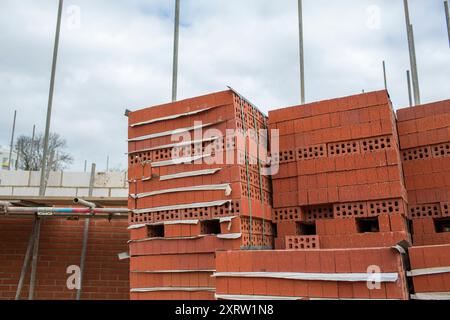 Grandi pallet di mattoni rossi in attesa di essere utilizzati in un nuovo progetto di costruzione di una casa. Foto Stock