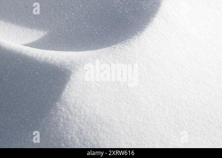Pieghe di neve che formano onde e forme astratte mentre è stato soffiato in schemi dal vento e accumulato in derive in siepi e sui fianchi della strada. Foto Stock