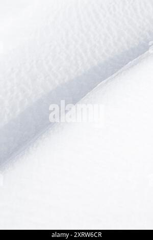 Pieghe di neve che formano onde e forme astratte mentre è stato soffiato in schemi dal vento e accumulato in derive in siepi e sui fianchi della strada. Foto Stock