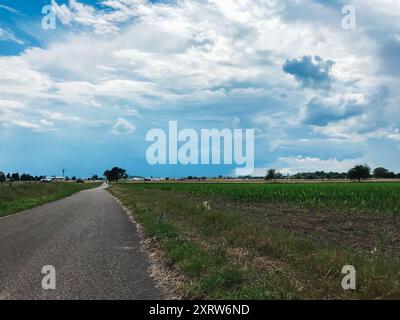 Una strada con un cielo nuvoloso sullo sfondo. Il cielo è per lo più nuvoloso con qualche pezzetto di blu Foto Stock