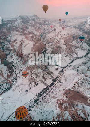Le mongolfiere sorvolano le valli innevate della Cappadocia all'alba, offrendo paesaggi invernali mozzafiato in questa iconica regione turca. Foto Stock