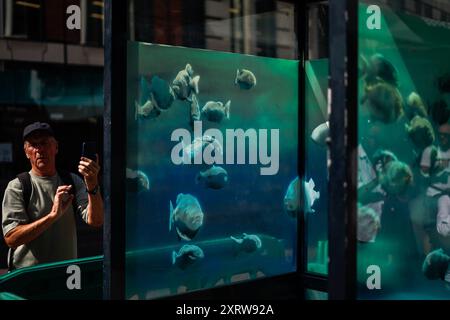 Londra, Regno Unito. 12 agosto 2024. La gente sta scattando foto di una nuova opera d'arte dell'artista di strada Banksy, che appare su una cabina della polizia nella City di Londra, il 12 agosto 2024. (Foto di Alberto Pezzali/NurPhoto) credito: NurPhoto SRL/Alamy Live News Foto Stock