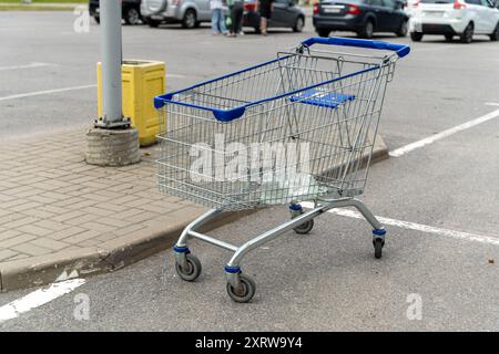 Un carrello si trova sul marciapiede, vicino a un palo luminoso, in un parcheggio. Foto Stock