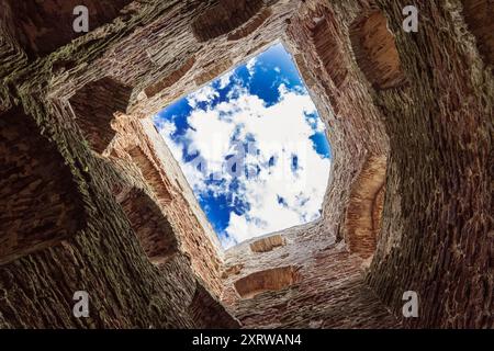 Guardando in alto un cielo blu vibrante attraverso un'antica apertura in pietra. Foto Stock