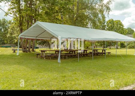 Una spaziosa tenda con panche è pronta per un evento all'aperto. Foto Stock